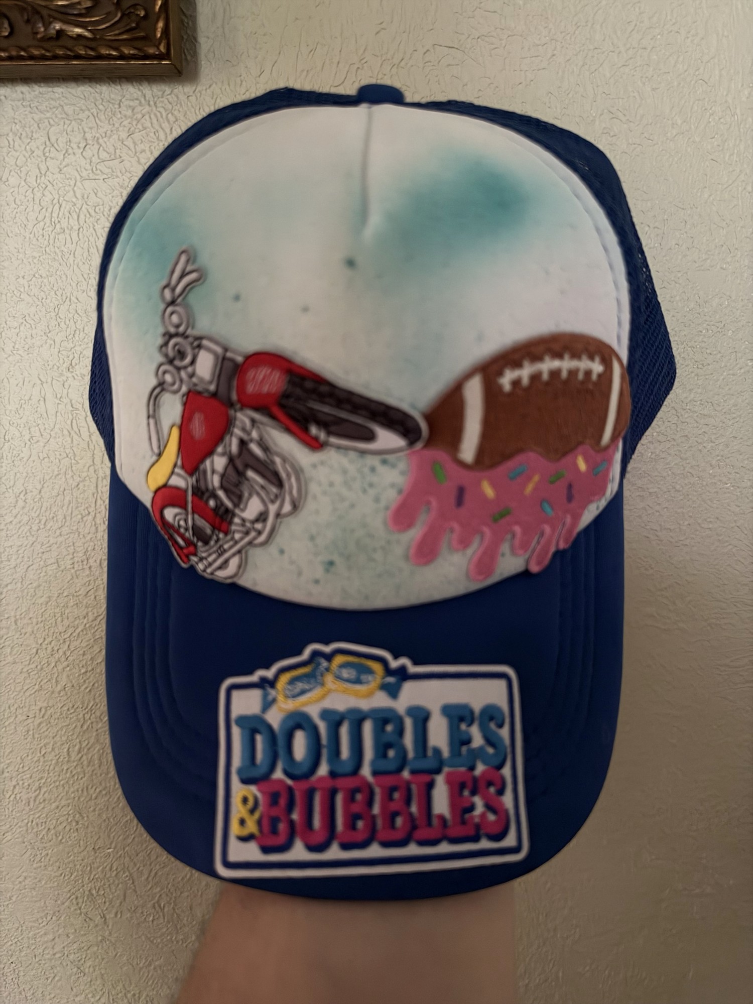Blue and white trucker hat with motorcycle, football, and Doubles & Bubbles patches